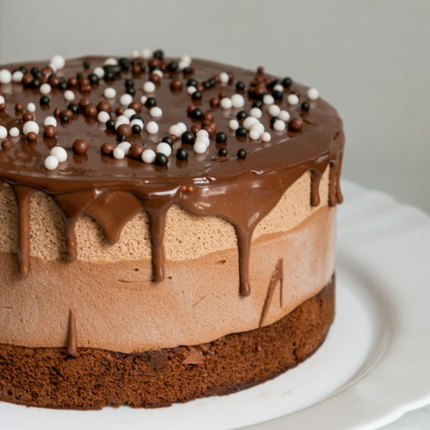 A dark chocolate ganache cake on a cake stand
